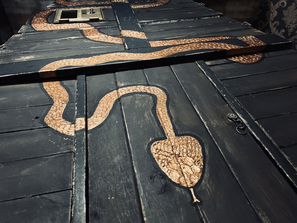 A strange, black box with a copper snake painted on its lid.