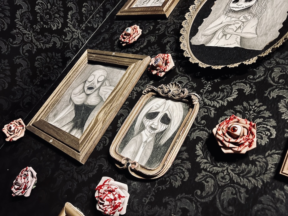 A wall covered in pencil art of nightmare creatures and bloody roses with human eyes in the center.