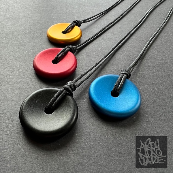 Deadeye wearable coins on a necklace string in 4 colors, yellow, red, black, and blue.