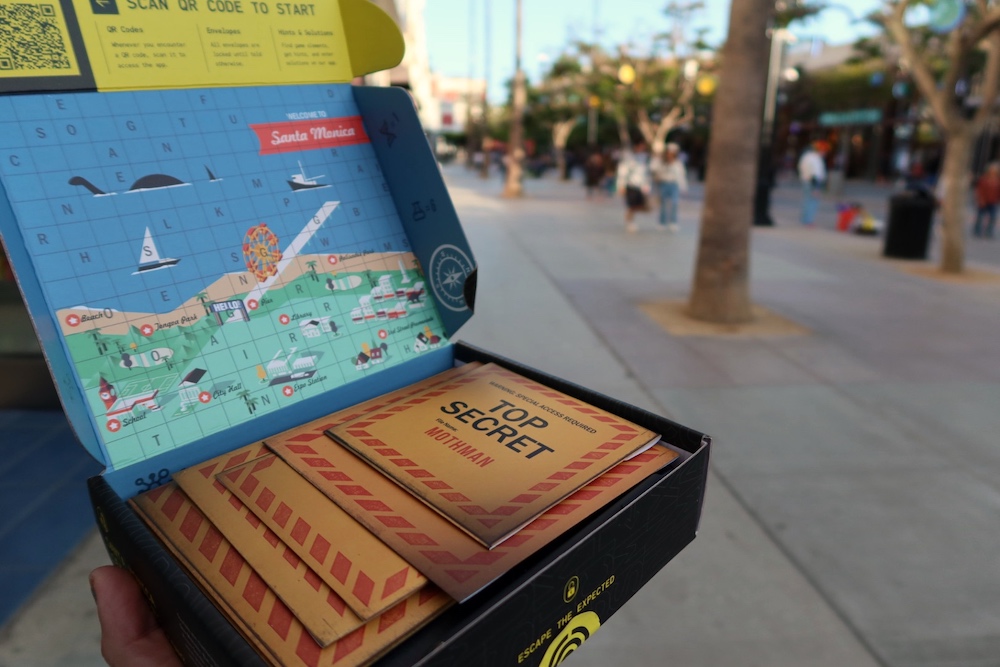 Hand holding an open Escapely box with a map of a puzzle-covered Santa Monica in Santa Monica.