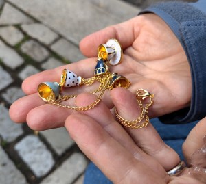 Hands holding a bracelet with an assortment of teacup charms.