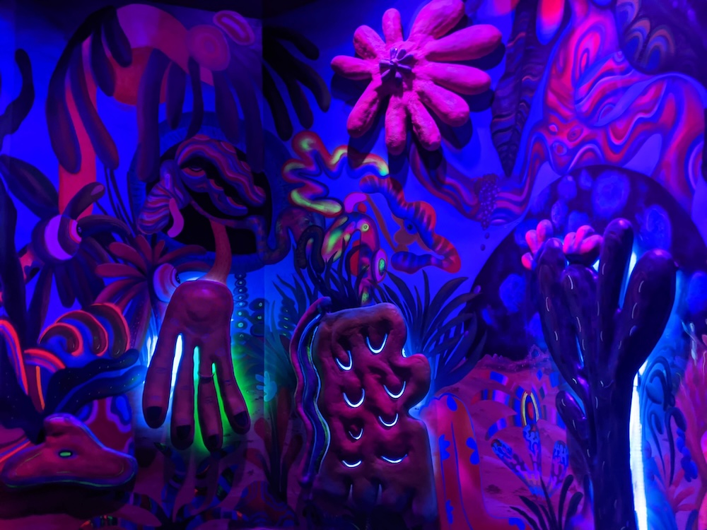 Purple psychedelic painted and sculpted wall of plant life.