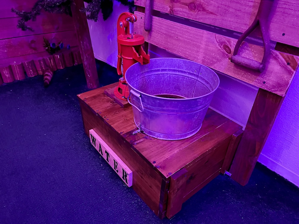 A water pump with a meta bucket under its spout.