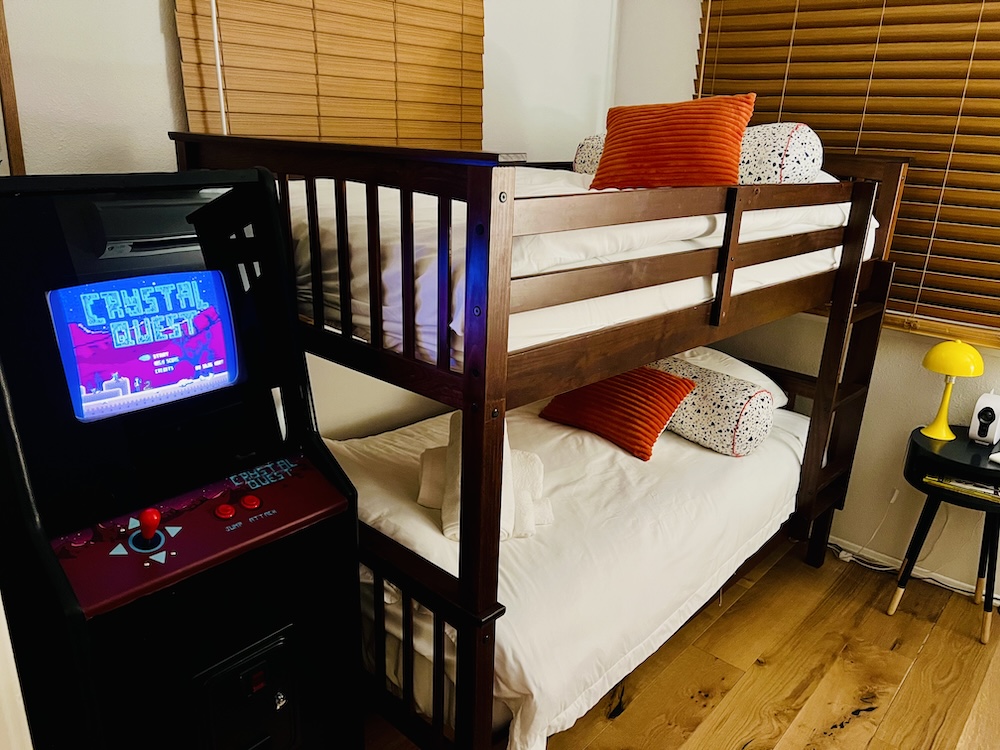 Childrens room with bunk beds and a custom arcade cabinet named, "Crystal Quest."