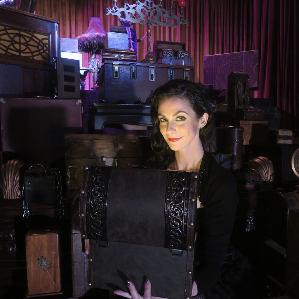 Woman standing in front of a wall of boxes, one box is in her hands open.