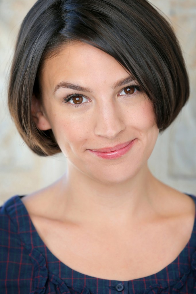 head shot of a pretty woman with brown eyes and a short brown bob and plaid blouse with a scoopneck.