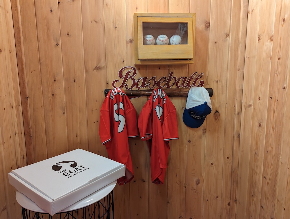 Hung baseball uniforms beside a display of baseballs.