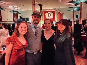Lisa, Brendan, Theresa P, Theresa W all dressed up at Club Dosselmeyer. The stage behind them.