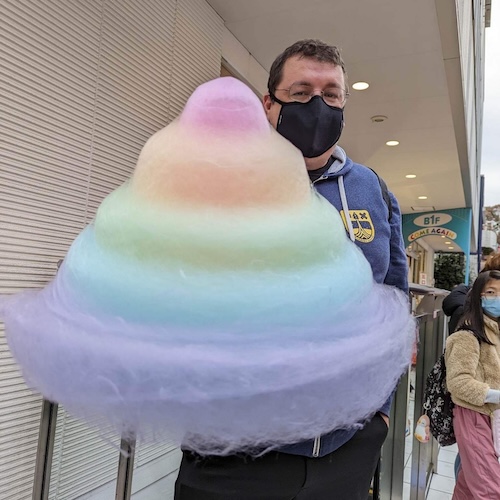 Ryan Brady holding a massive, multi-colored, mountain of cotton candy.