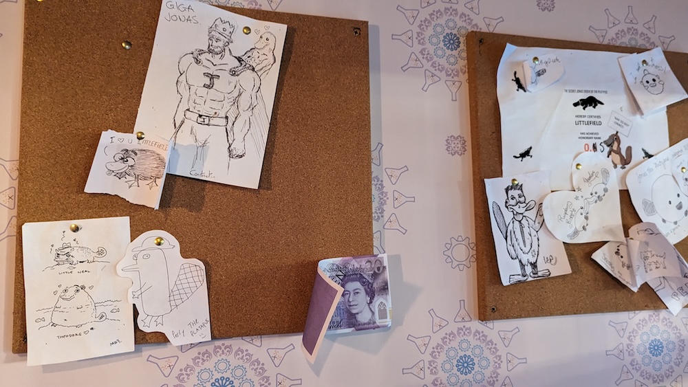 A billboard with assorted illustrations of things and people from around Phantom Peak including Platman. 