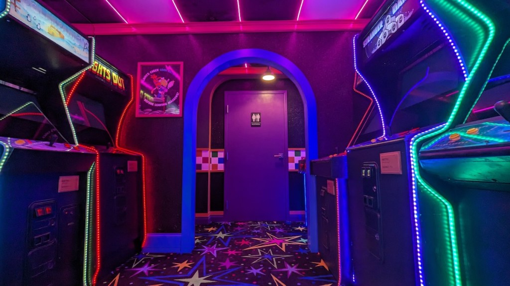 A neon lit arcade with an assortment of arcade cabinets.