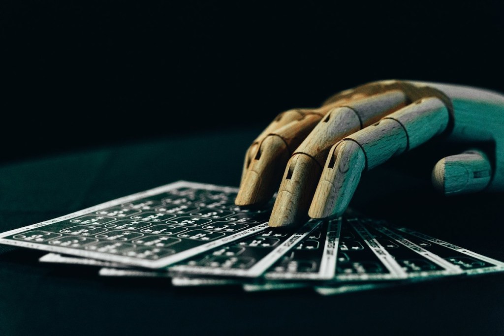 A wooden hand holding 6 fanned out cards.