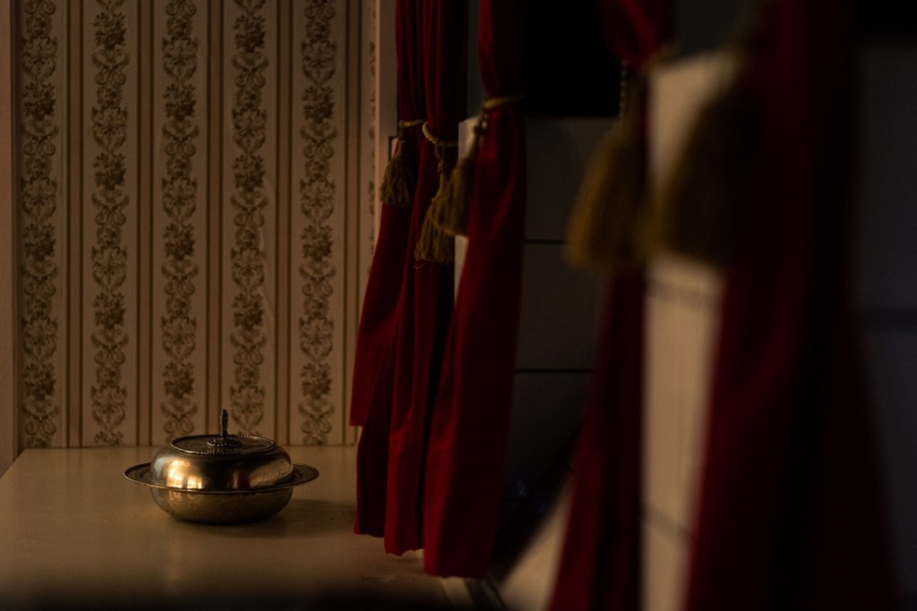 a metal dish with a metal lid on a table with wallpaper in the background