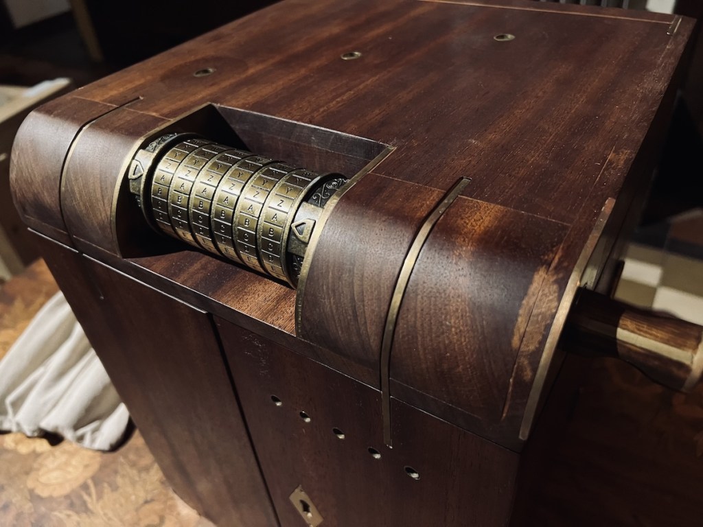 A wooden box with a cryptex set against it, locking it.