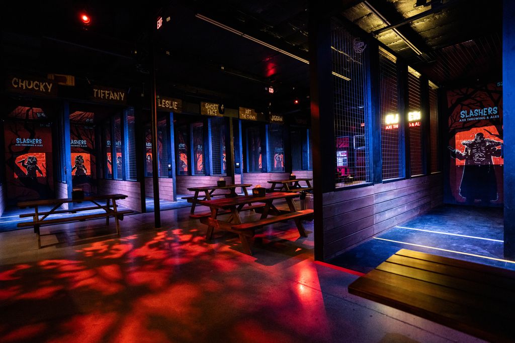 axe throwing venue with projections of illustrated horror characters and picnic tables