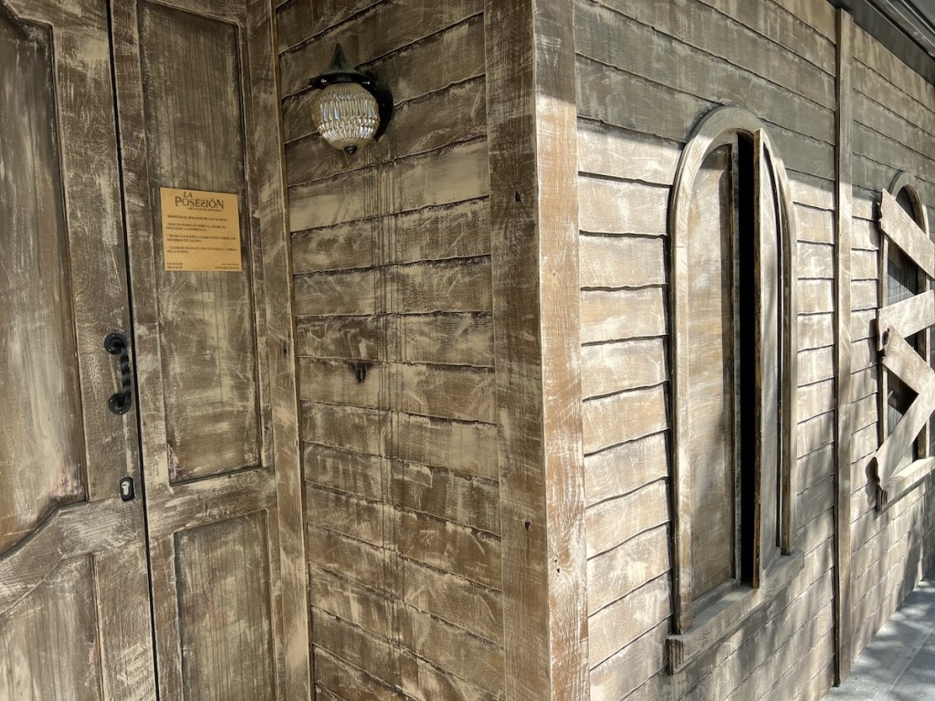 An old wood house exterior with boarded up windows.