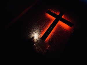 A cross, lit red in darkness.