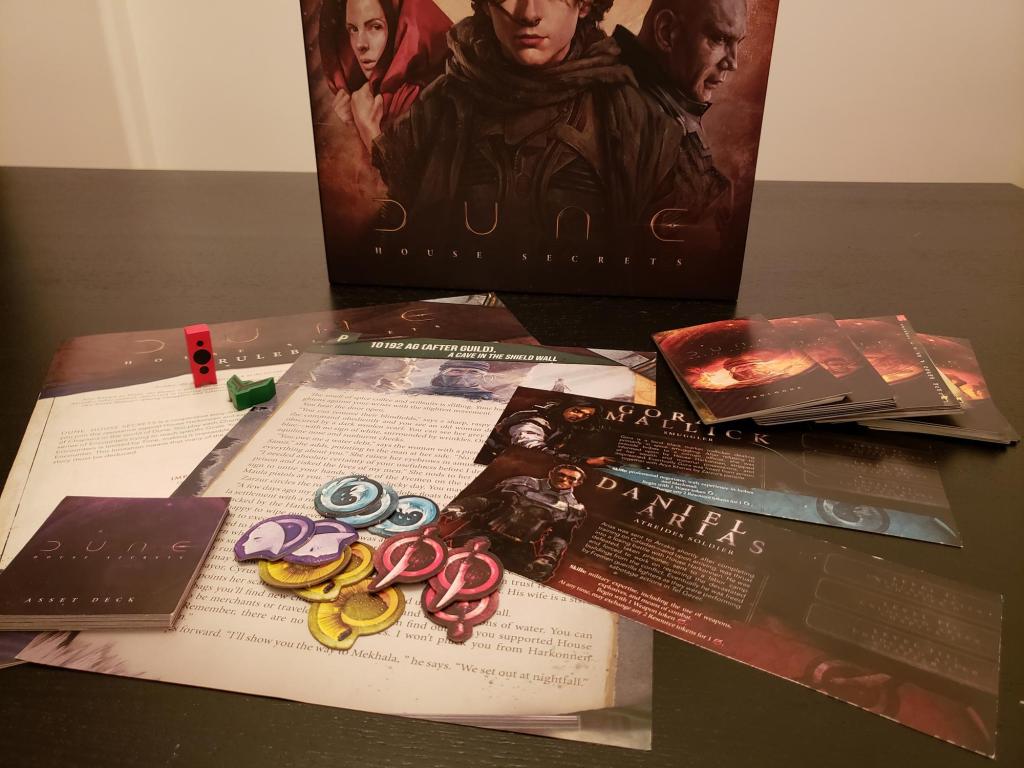 An assortment of colorful game components beside the Dune box.