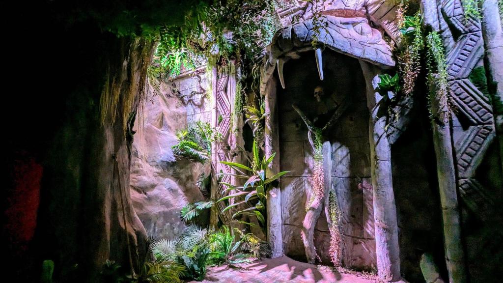 An ancient temple with a stone structure looking like a venomous snake's open mouth with a human skeleton within it.