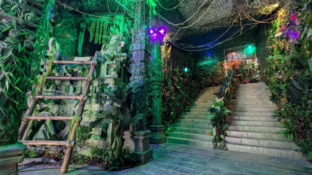 A large stairwell, decorated like a jungle with a lashed together wooden ladder.