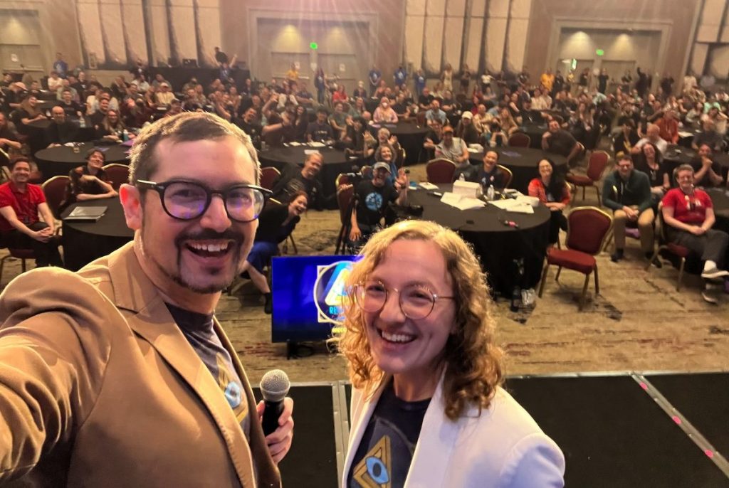 David and Lisa on-stage at RECON taking a selfie of a very full audience.
