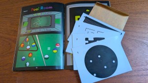An assortment of puzzle components beside a book opened to a page featuring a billiards puzzle.