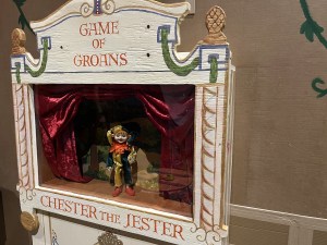 A little doll stands on a tiny stage labeled, "Game of Groans, Chester the Jester."