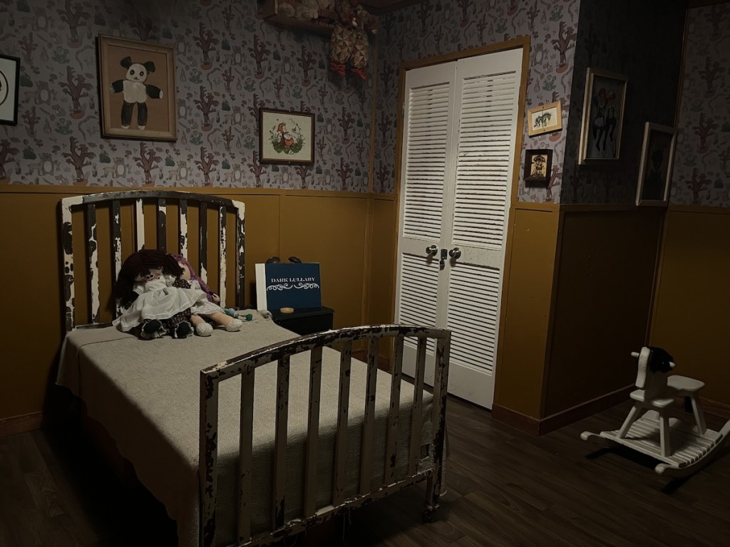 A dim and grim child's room with dolls resting on a beat up, old bed.