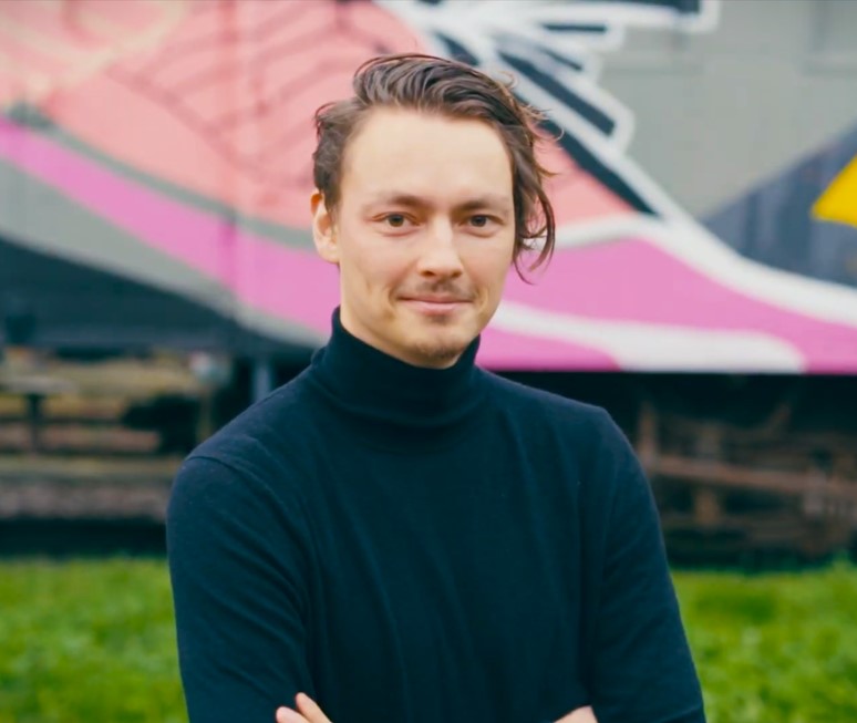 Man with sideswept hair and a small goatee wearing a dark blue turtleneck