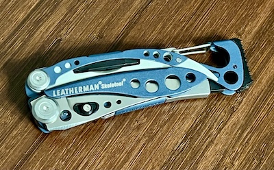 Folded up steel with green trim Leatherman Skeletool multi-tool with a mallet modified base. 