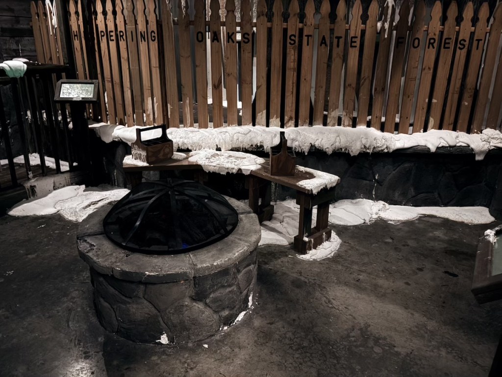 A campfire pit with benches around it. Beyond is a wood fence.