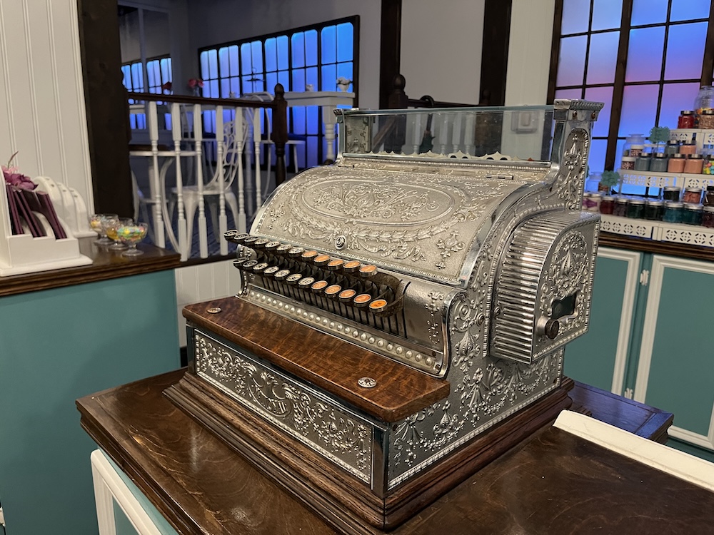 An old cash register in the middle of a bright candy shop.