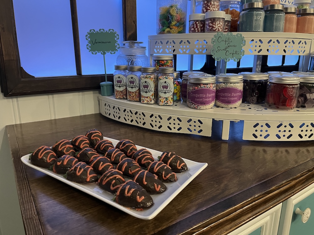 A counter in a candy show with chocolate treats and bottles of sugary sweets.
