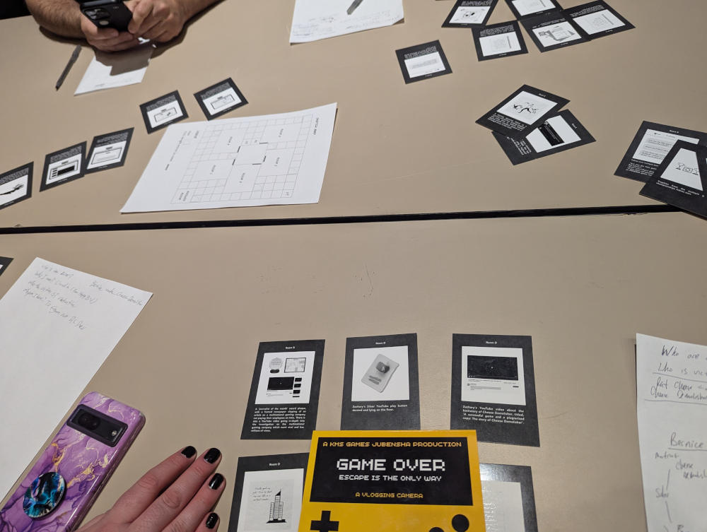A table with many small cards in front of multiple players. The cards represent pieces of evidence used in KMS Games' Game Over.