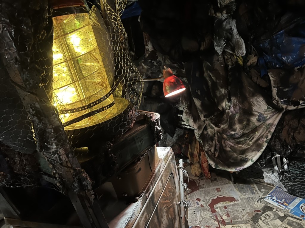 A pile of garbage including a washing machine, luggage, and old lamps.