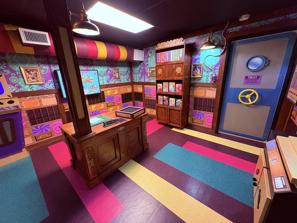 Wide view of the Candy Factory, a brightly colored space that looks like a strange office decorated with candy.