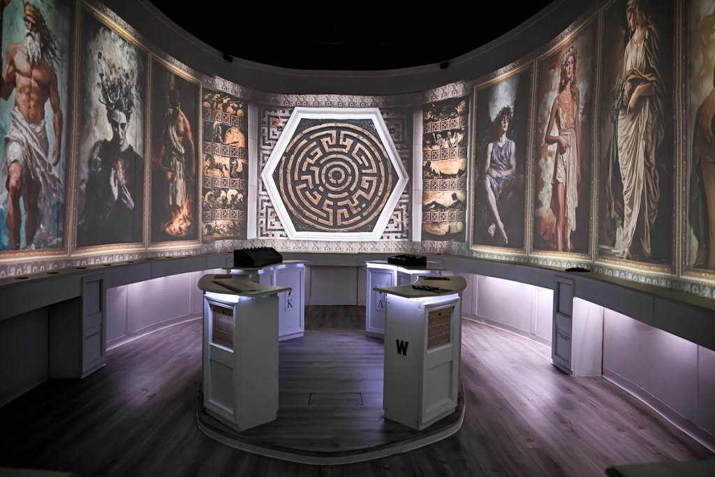 A large room with portraits of Greek Gods and an image of a labyrinth.