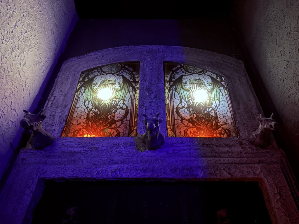 Stained Glass featuring a green winged and tentacled monster above the entrance of the Chapel of Dagon.