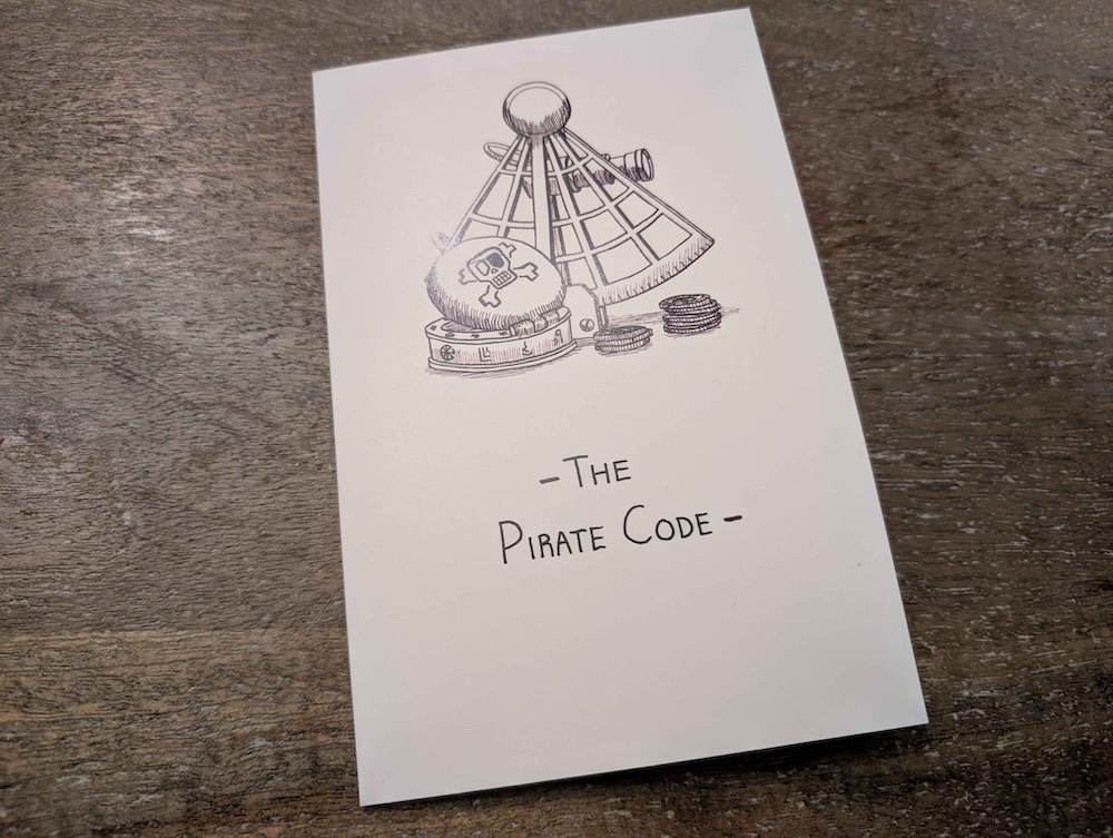 The Pirate Code puzzle card with a sextant, some coins, and a stone with a jolly roger.