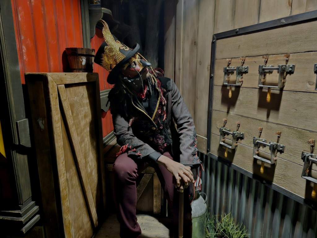 A masked circus worker staring at a series of large switches.