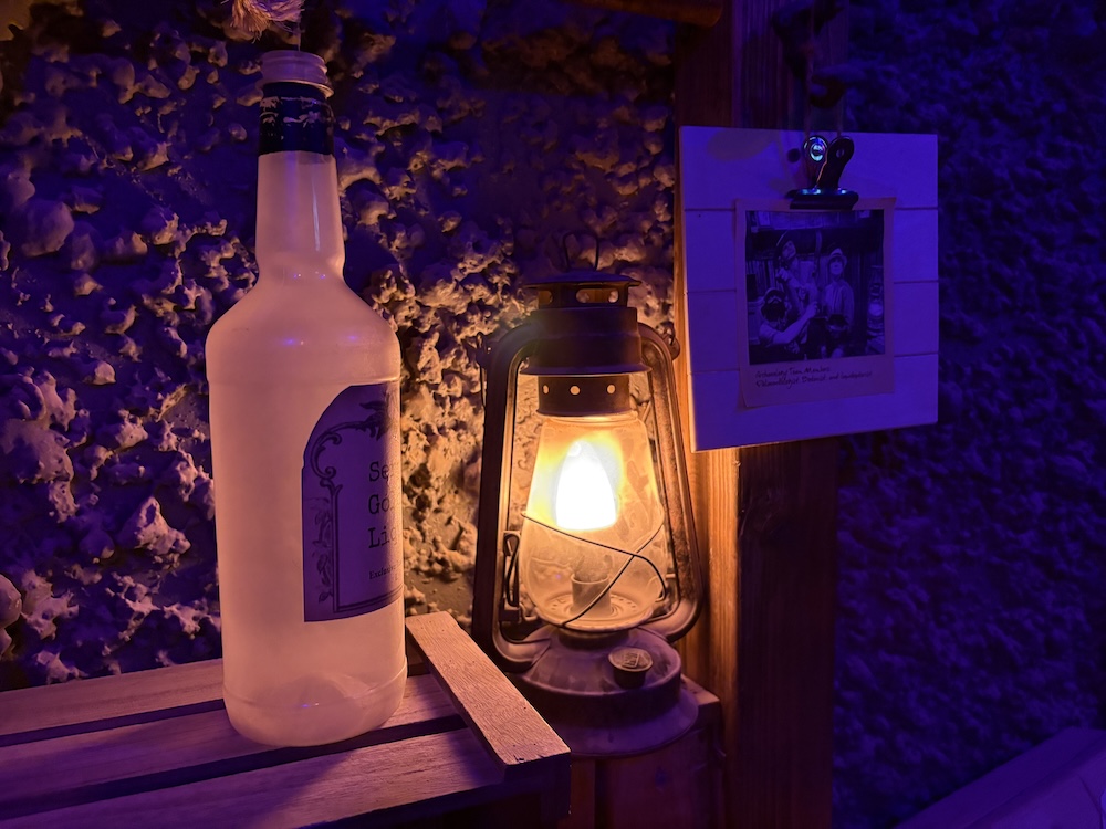 An empty liquor bottle beside a glowing lantern.