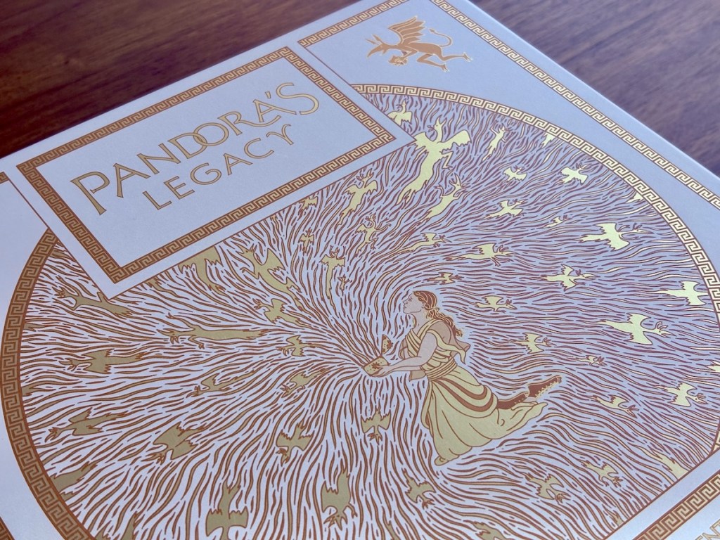 Box for Pandora's Legacy, depicting Pandora opening the box rendered in gold foil against a white background.