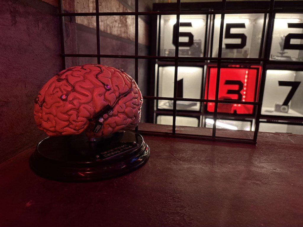 A human brain covered in electrodes behind a cage.