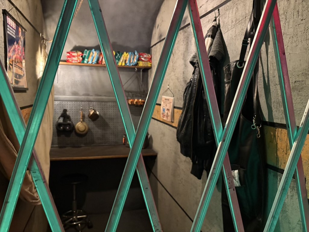 An alcove with food and gear behind a retractable gate.