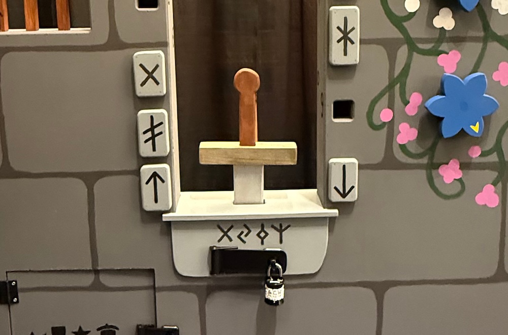 A wooden sword set within the window of a castle wall surrounded by flowers and runes.