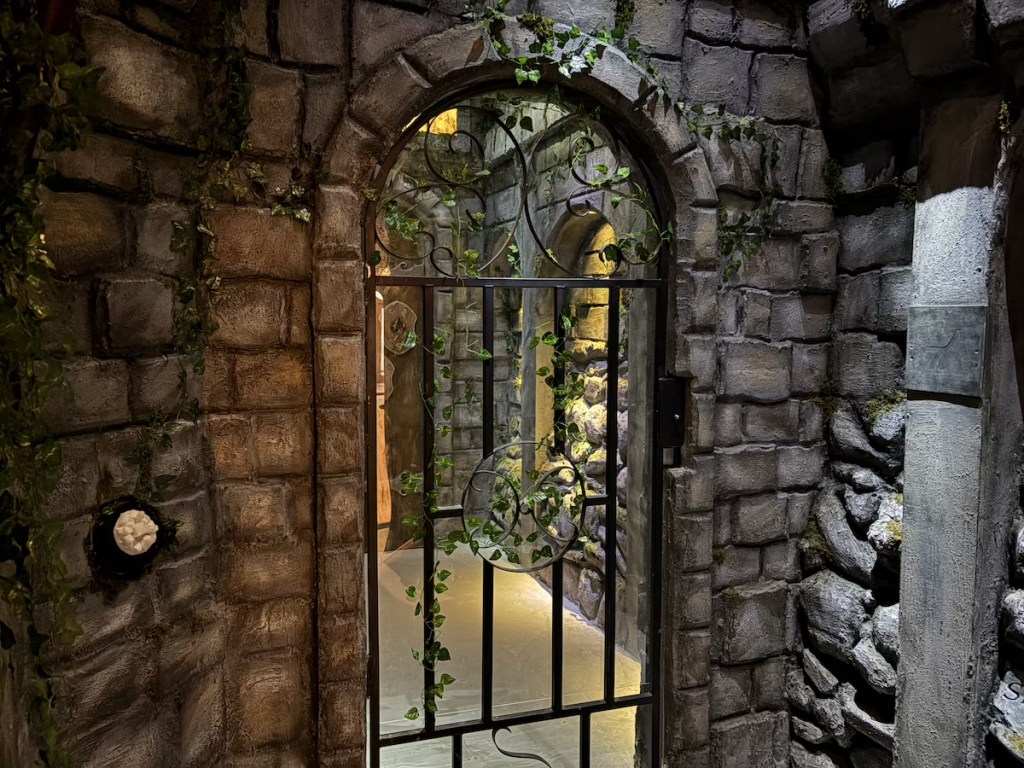 A stone wall and portico with an ivy-covered gate.