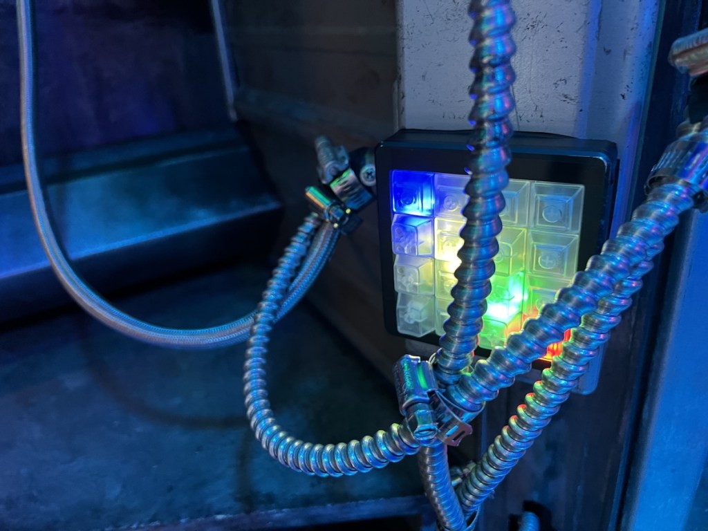 Closeup of an illuminated keypad with metal wire tubing hanging in front of it.