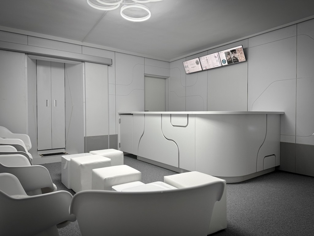 A futuristic white lobby with a front desk and seating in a waiting area.