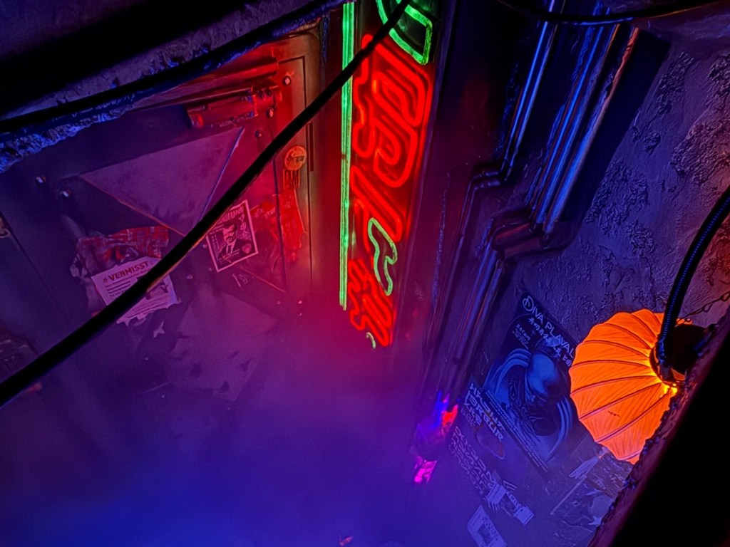 A cyberpunk alleyway, heavily worn, illuminated by a neon sign.