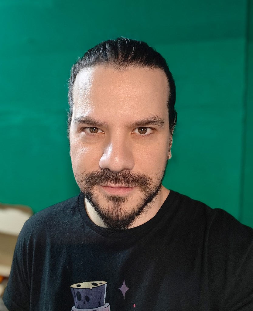 man with long dark hair pulled back in a ponytail with goatee and wearing a black t-shirt